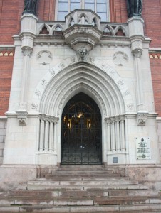 Järngrind i västra entrén. Porten bär formen av en typisk lansettbåge och har arkivolter.